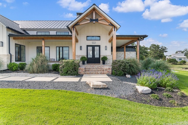 doorway to property featuring covered porch, french doors, a yard, board and batten siding, and a standing seam roof