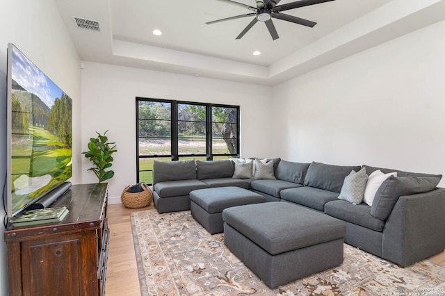 living room featuring a ceiling fan, recessed lighting, visible vents, a raised ceiling, and light wood-type flooring