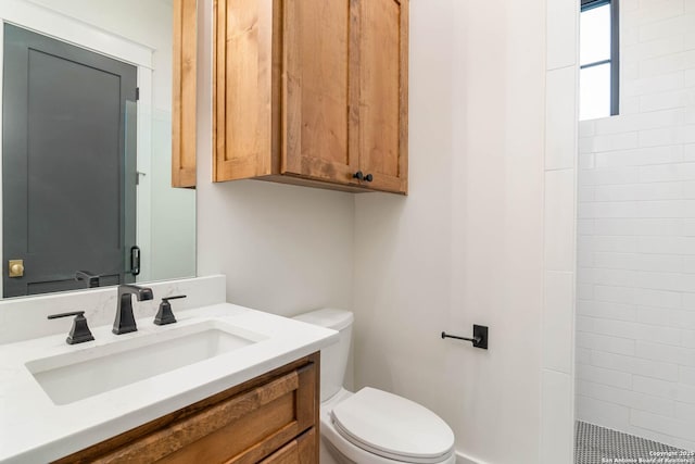 bathroom with vanity, toilet, and a tile shower