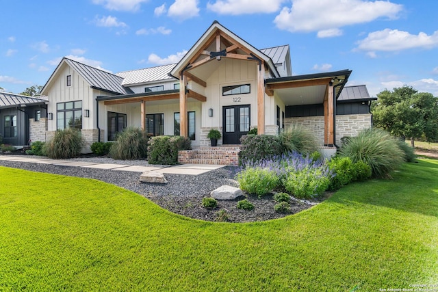 view of front of property with french doors, metal roof, a front lawn, board and batten siding, and a standing seam roof