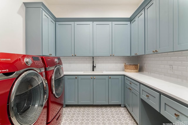 laundry area featuring cabinet space, independent washer and dryer, light floors, and a sink