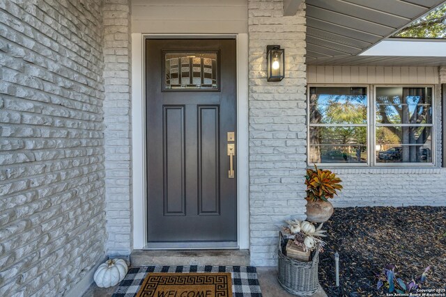 doorway to property featuring a porch and brick siding