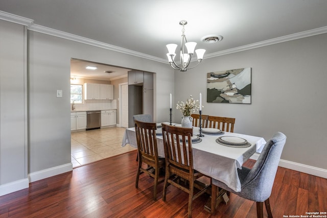 dining area featuring a notable chandelier, baseboards, ornamental molding, visible vents, and wood finished floors