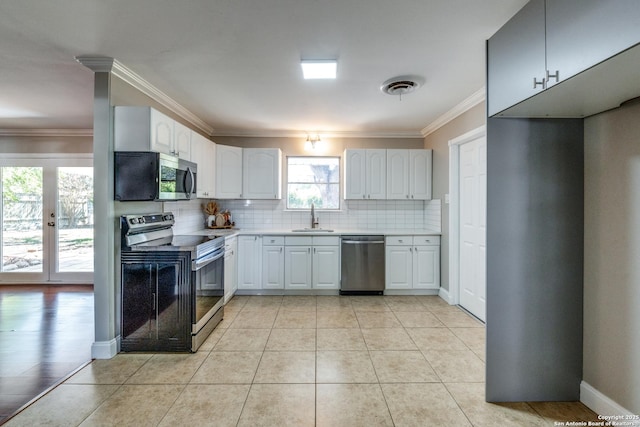 kitchen featuring ornamental molding, a sink, light countertops, tasteful backsplash, and appliances with stainless steel finishes
