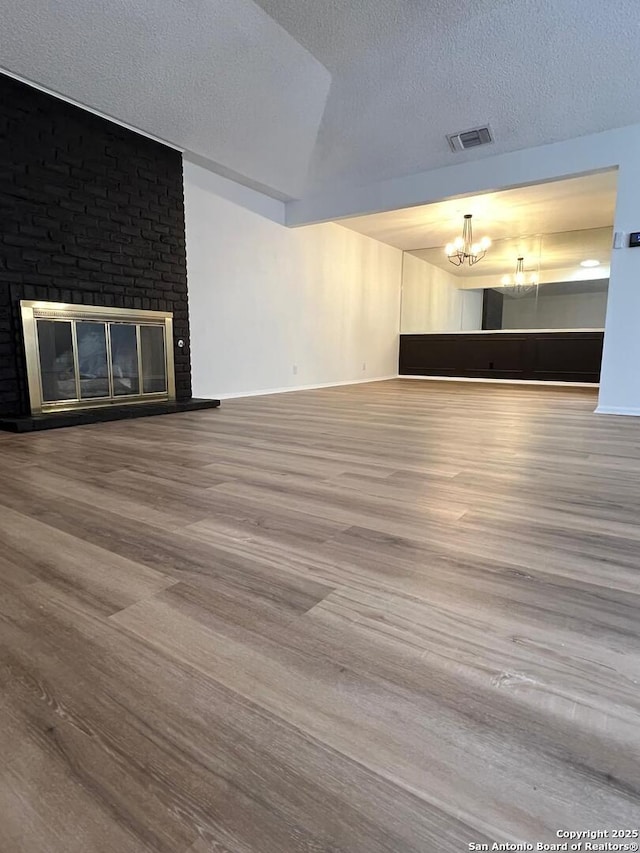 10106 Grand Park, San Antonio, TX 78239 - unfurnished living room featuring a textured ceiling, baseboards, an inviting chandelier, visible vents, and wood finished floors
