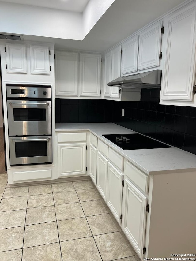10106 Grand Park, San Antonio, TX 78239 - kitchen with under cabinet range hood, light tile patterned floors, backsplash, black electric stovetop, and double oven