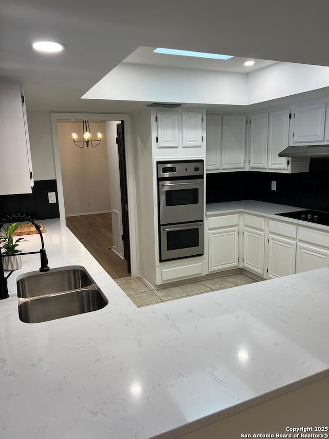 10106 Grand Park, San Antonio, TX 78239 - kitchen featuring a sink, stainless steel double oven, decorative backsplash, black electric cooktop, and a notable chandelier
