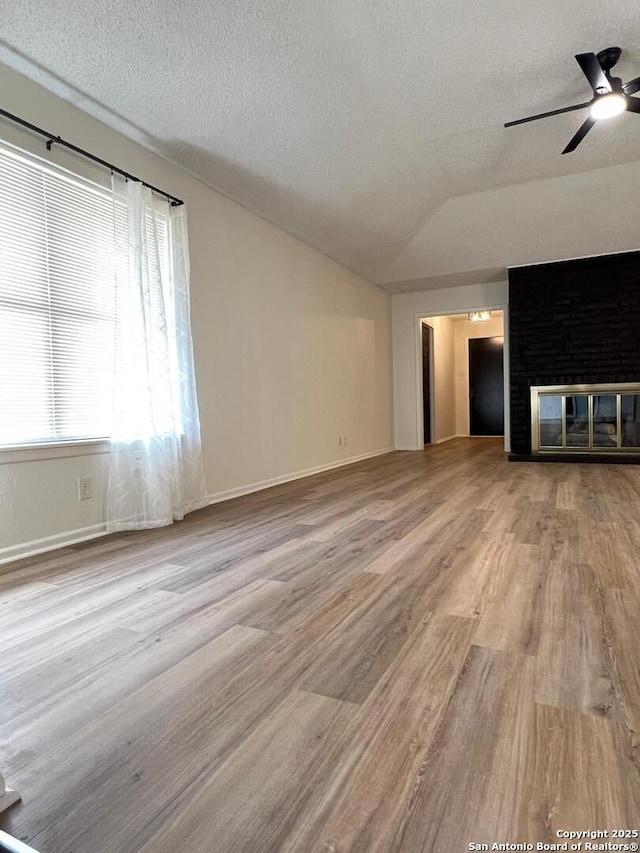 10106 Grand Park, San Antonio, TX 78239 - unfurnished living room featuring a ceiling fan, a fireplace, a textured ceiling, and vaulted ceiling