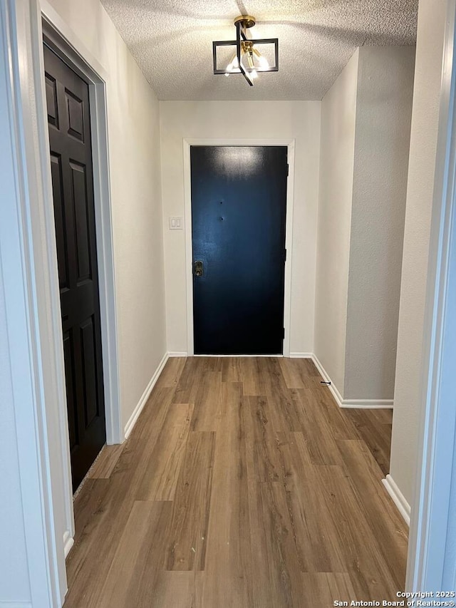 10106 Grand Park, San Antonio, TX 78239 - doorway to outside featuring a textured ceiling, baseboards, and wood finished floors