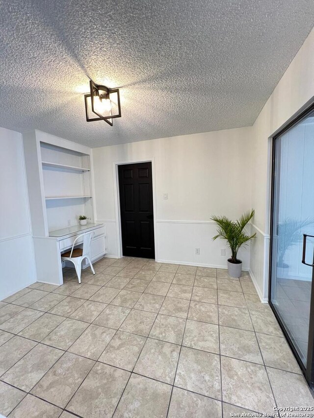 10106 Grand Park, San Antonio, TX 78239 - unfurnished dining area featuring a textured ceiling, light tile patterned floors, and built in shelves