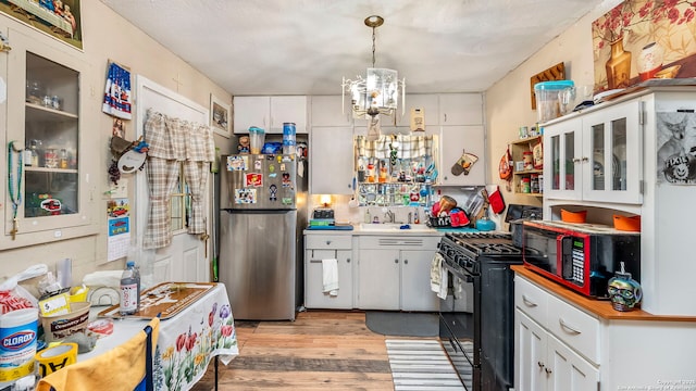 237 Delmar, San Antonio, TX 78210 - kitchen with a sink, black appliances, light wood finished floors, a chandelier, and white cabinetry