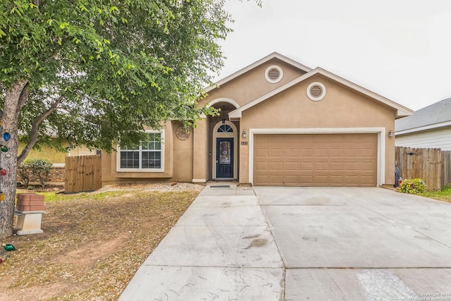 view of front of property featuring concrete driveway, an attached garage, stucco siding, and fence