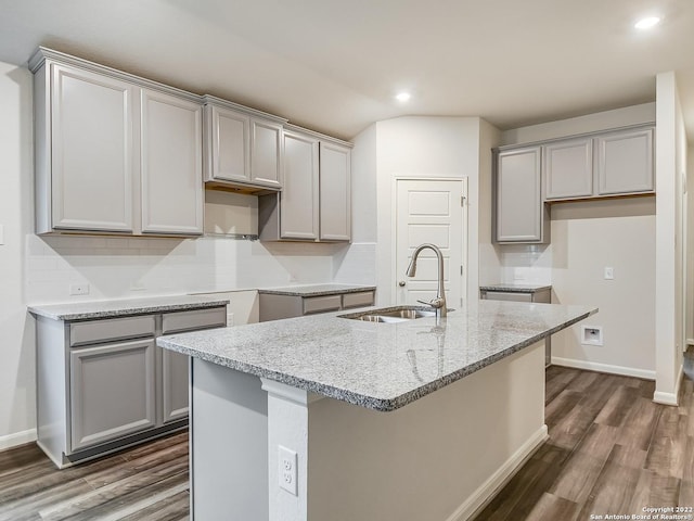 4532 Appaloosa Crst, San Antonio, TX 78245 - kitchen with light stone countertops, dark wood finished floors, a sink, a center island with sink, and gray cabinets
