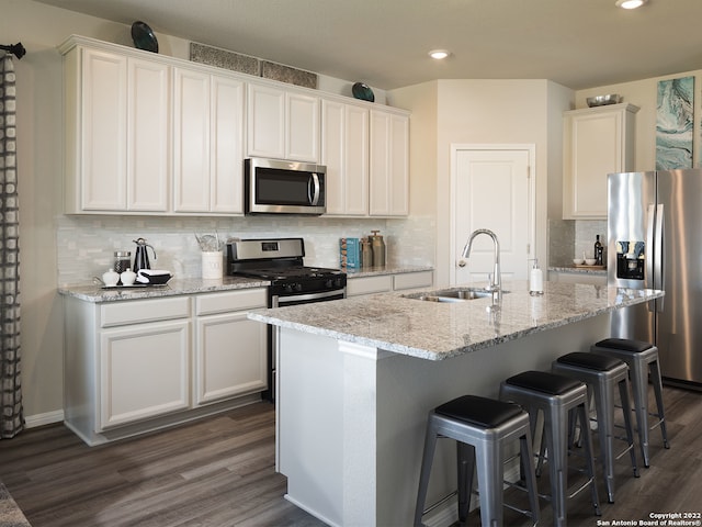 4539 Appaloosa Crst, San Antonio, TX 78245 - kitchen with dark wood-style flooring, a sink, decorative backsplash, a center island with sink, and appliances with stainless steel finishes