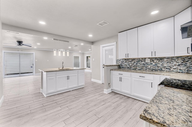 kitchen with a ceiling fan, baseboards, a sink, white cabinetry, and backsplash