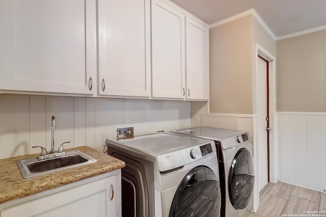 laundry room featuring separate washer and dryer, cabinet space, ornamental molding, a decorative wall, and a wainscoted wall
