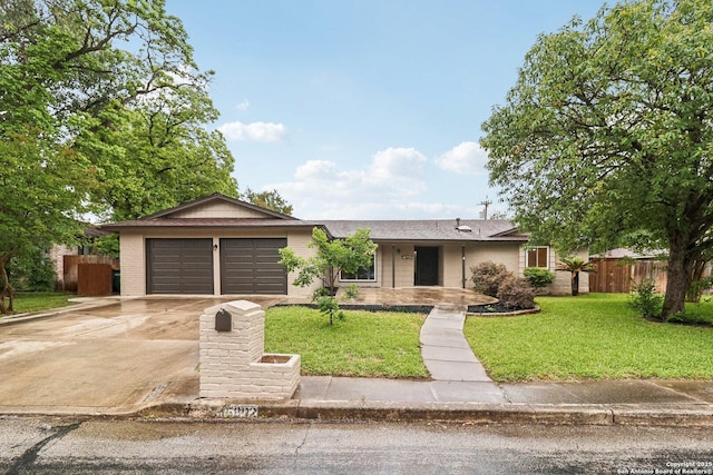 ranch-style house featuring brick siding, fence, an attached garage, concrete driveway, and a front lawn