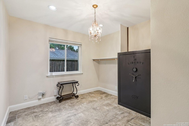 empty room with a notable chandelier, baseboards, and recessed lighting