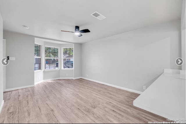 unfurnished room featuring a ceiling fan, baseboards, visible vents, and wood finished floors