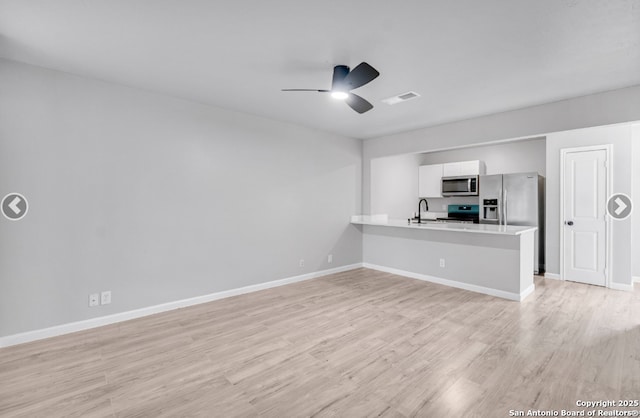 interior space with stainless steel appliances, light wood-type flooring, visible vents, ceiling fan, and light countertops