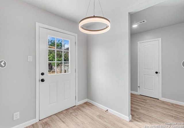 doorway featuring light wood-type flooring, visible vents, and baseboards