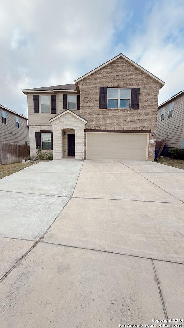 8411 Puente, San Antonio, TX 78223 - traditional-style home with driveway, brick siding, fence, a garage, and stone siding