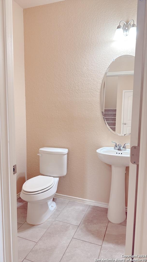 8411 Puente, San Antonio, TX 78223 - bathroom with tile patterned floors, toilet, baseboards, and a sink
