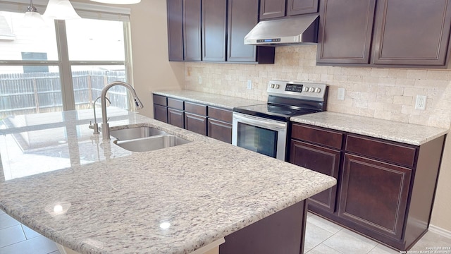 8411 Puente, San Antonio, TX 78223 - kitchen with light tile patterned floors, a sink, stainless steel range with electric cooktop, a center island with sink, and wall chimney range hood