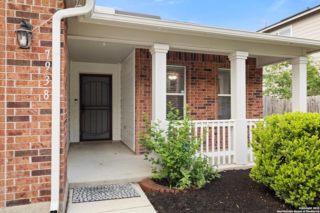 doorway to property with a porch and brick siding
