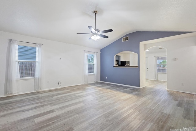unfurnished living room with vaulted ceiling, light wood-type flooring, visible vents, and ceiling fan
