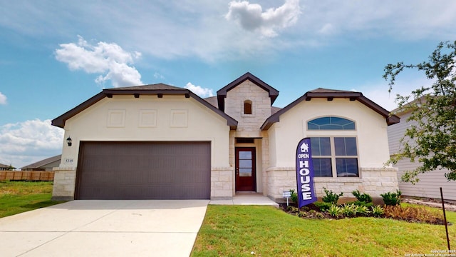 mediterranean / spanish-style home featuring stone siding, driveway, an attached garage, and a front yard