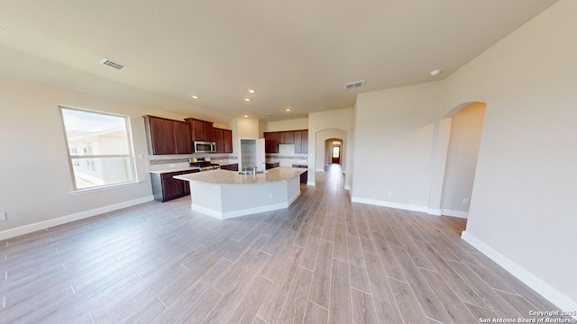 kitchen featuring stainless steel appliances, visible vents, arched walkways, light countertops, and light wood-style floors