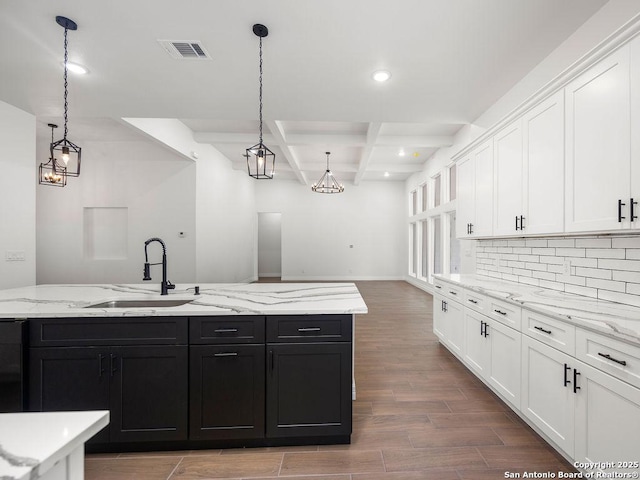 kitchen with white cabinets, coffered ceiling, dark cabinets, and a sink