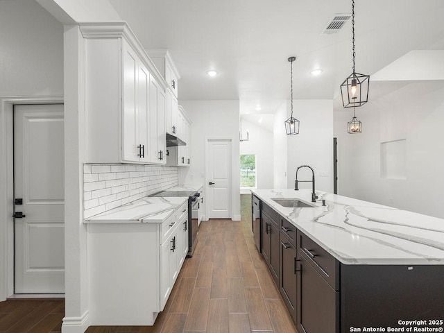 kitchen with a sink, white cabinets, dark wood-type flooring, a large island, and appliances with stainless steel finishes