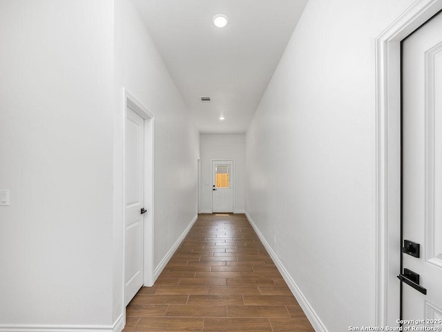 corridor with dark wood-type flooring, baseboards, visible vents, and recessed lighting