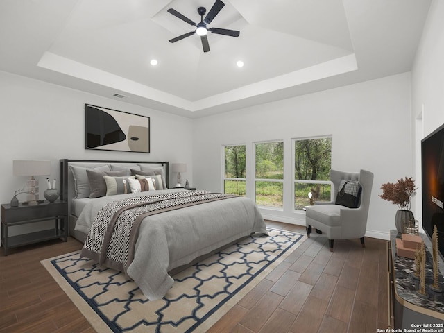 bedroom with a tray ceiling, dark wood-style flooring, a ceiling fan, and recessed lighting