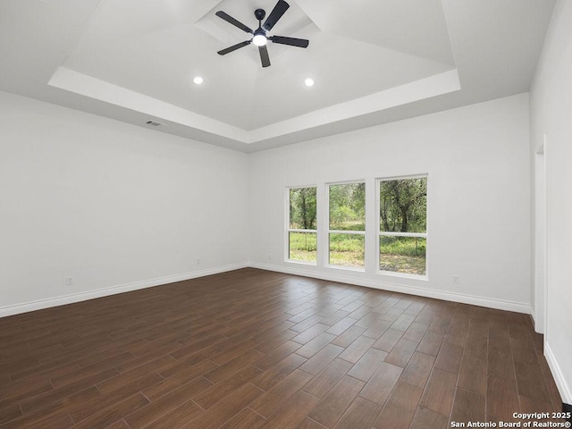 unfurnished room featuring recessed lighting, dark wood finished floors, ceiling fan, a raised ceiling, and baseboards