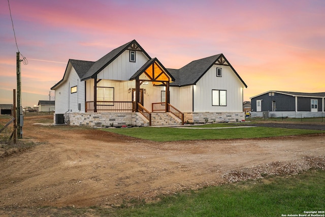 modern farmhouse style home with board and batten siding, central AC, and a lawn