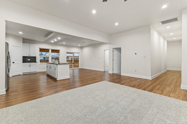 kitchen featuring visible vents, white cabinetry, open floor plan, stainless steel fridge, and dark wood-type flooring