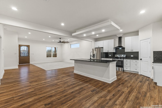 kitchen with wall chimney range hood, dark wood finished floors, dark countertops, and appliances with stainless steel finishes