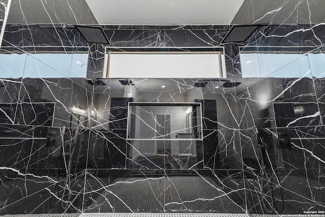 interior details featuring a marble finish shower