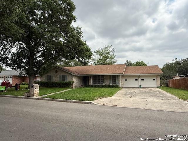 ranch-style home with an attached garage, driveway, fence, and a front lawn