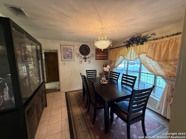 dining space with a notable chandelier, visible vents, and light tile patterned flooring