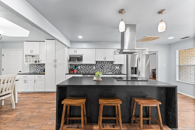 503 Lower Lacoste, Castroville, TX 78009 - kitchen with island exhaust hood, dark countertops, stainless steel appliances, white cabinets, and backsplash
