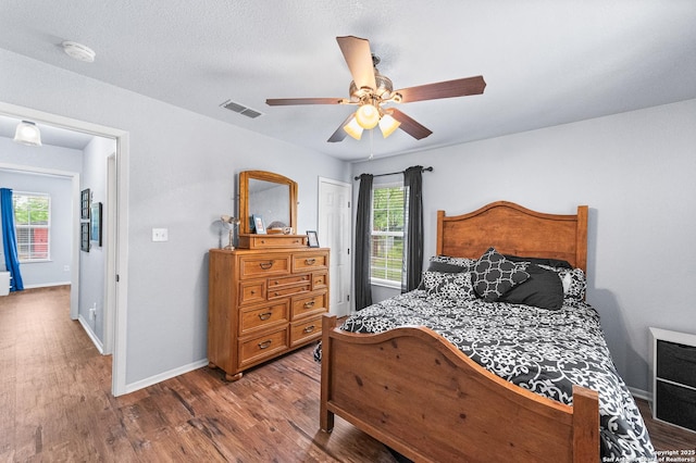 503 Lower Lacoste, Castroville, TX 78009 - bedroom with wood finished floors, visible vents, ceiling fan, heating unit, and baseboards
