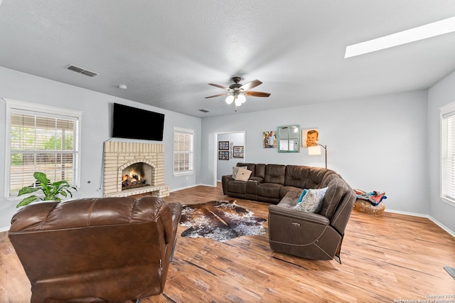 503 Lower Lacoste, Castroville, TX 78009 - living room featuring wood finished floors, visible vents, ceiling fan, a brick fireplace, and baseboards