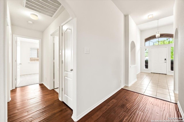 entrance foyer with visible vents, baseboards, arched walkways, and hardwood / wood-style flooring