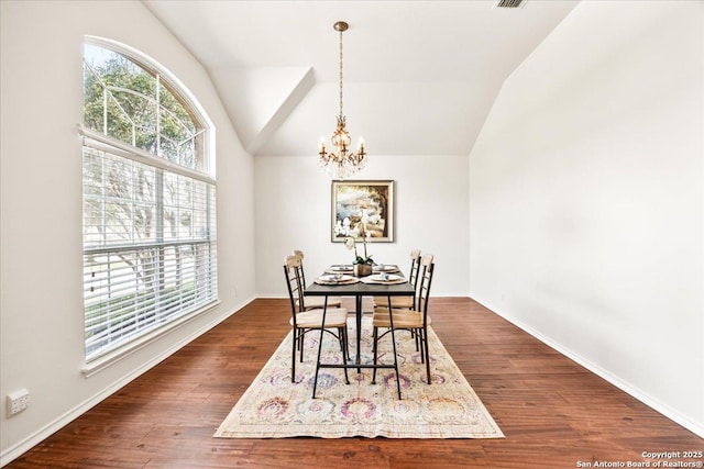 dining area featuring an inviting chandelier, vaulted ceiling, dark wood-style flooring, and baseboards