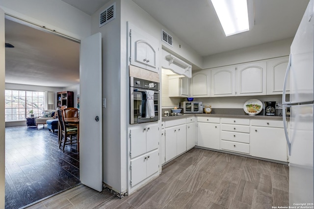 7500 Callaghan Rd Unit 172, San Antonio, TX 78229 - kitchen featuring freestanding refrigerator, wood finish floors, visible vents, and stainless steel oven