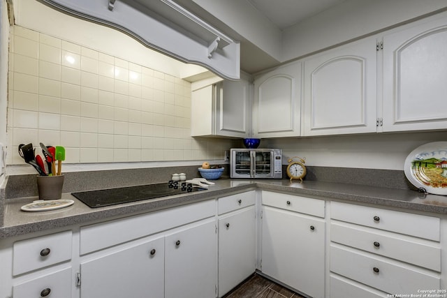 7500 Callaghan Rd Unit 172, San Antonio, TX 78229 - kitchen with a toaster, dark countertops, decorative backsplash, black electric cooktop, and white cabinets